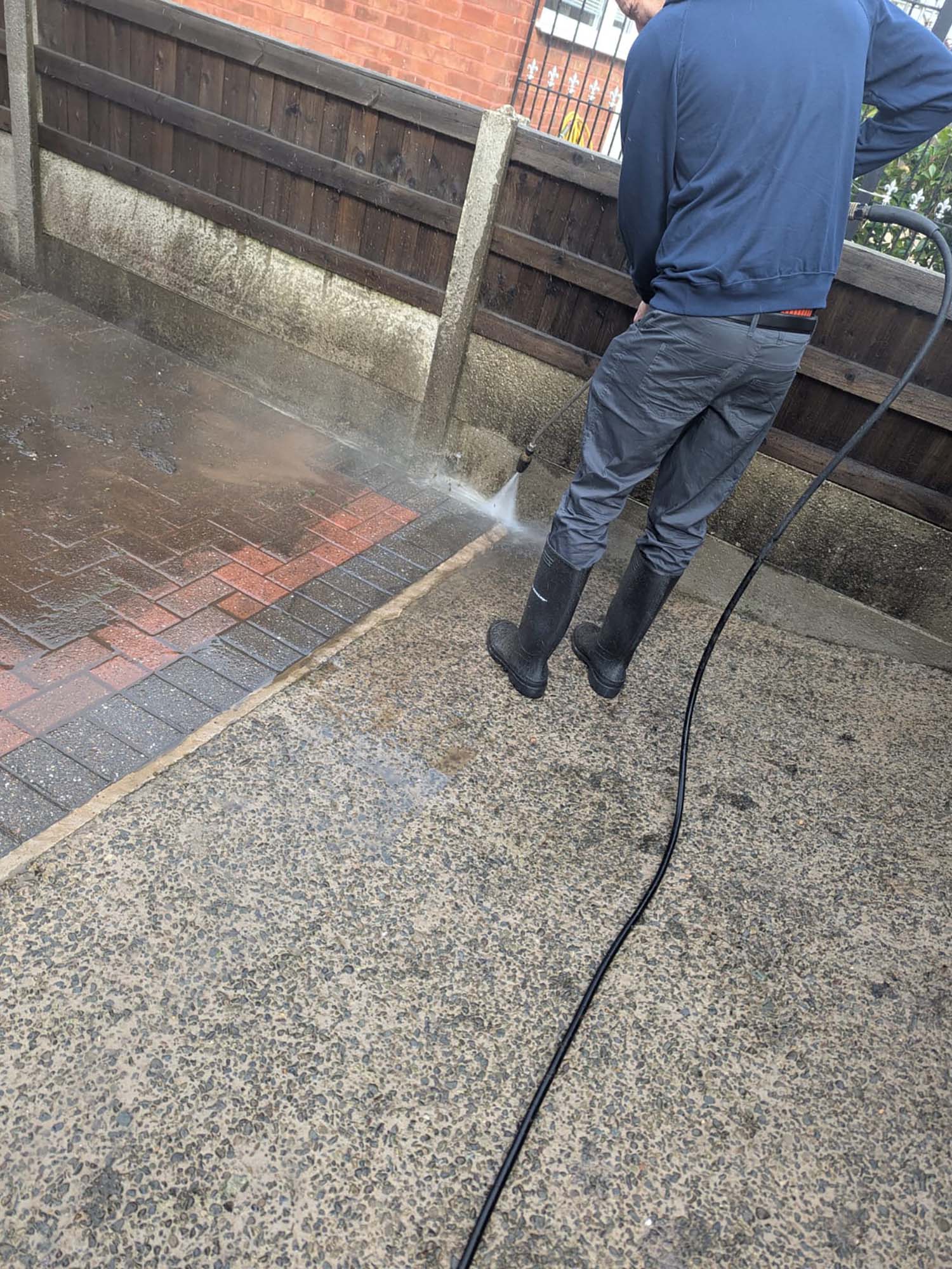 Man jet washing block paved driveway