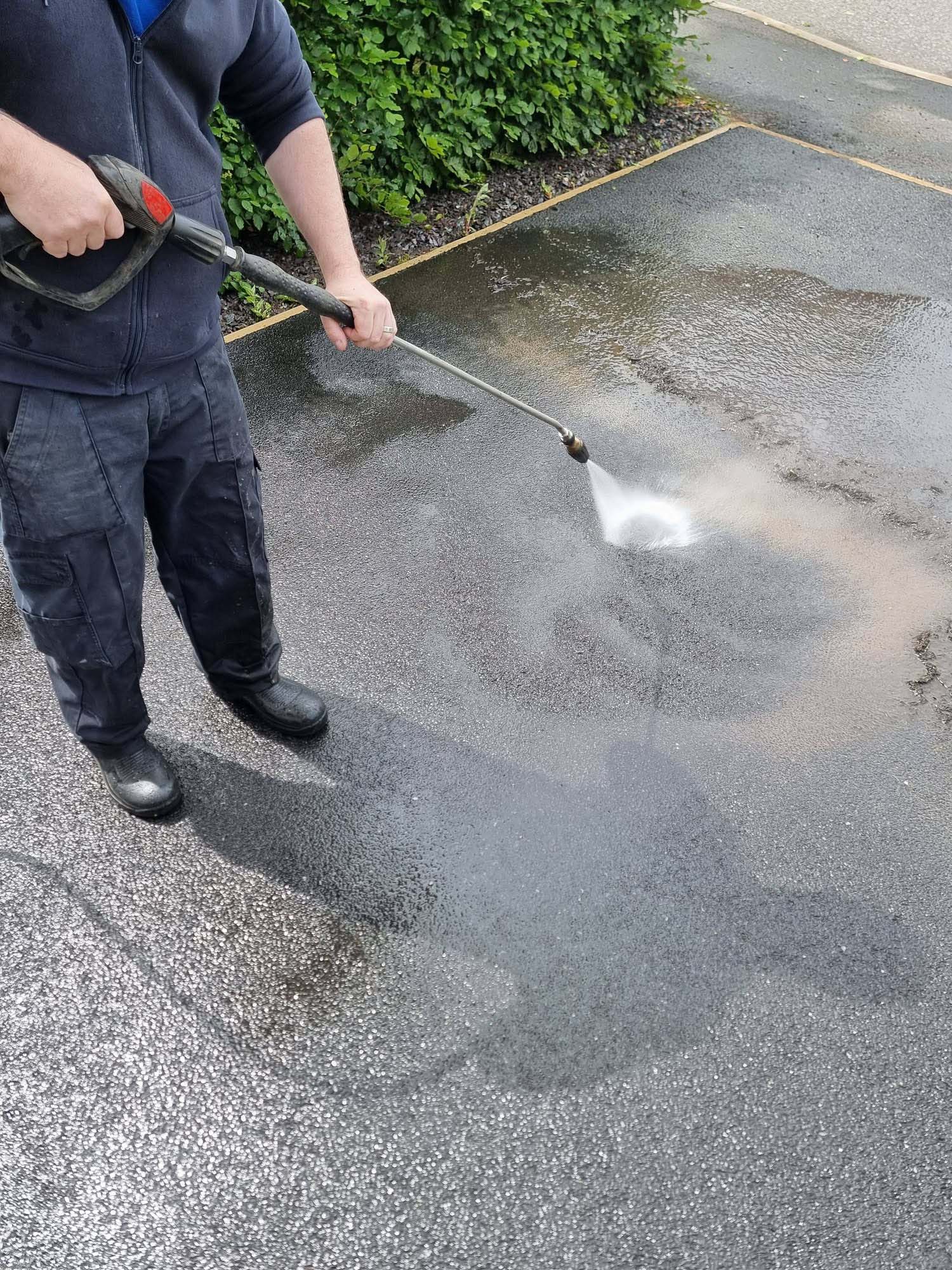 Man jet washing tarmac driveway