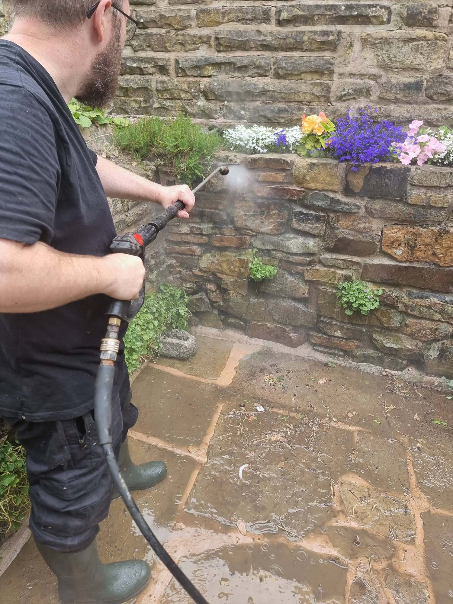 Man jet washing stone wall