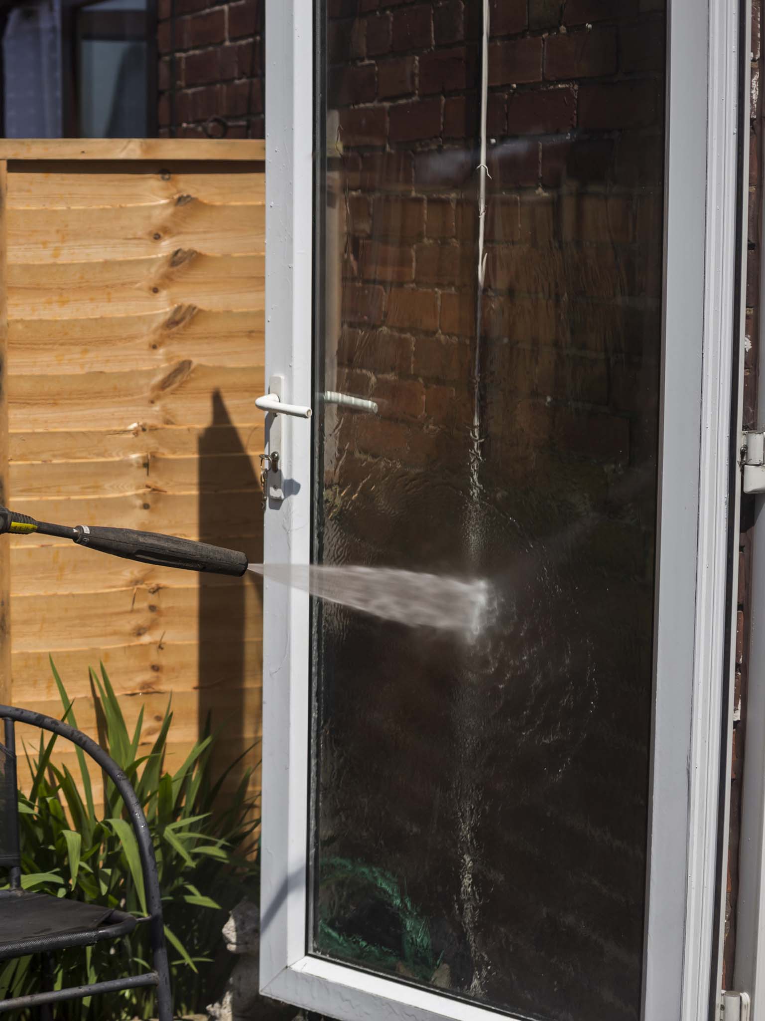 Man using a pressure washer to clean windows